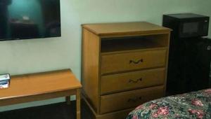 a bedroom with a wooden dresser and a desk at Budget Inn Franklinton in Franklinton