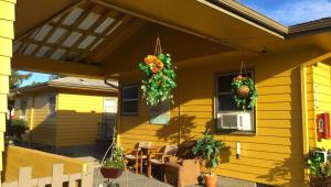 ein gelbes Haus mit Blumen, die von einer Veranda hängen in der Unterkunft Windmill Inn Lynden in Lynden