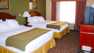 a hotel room with two beds and a flat screen tv at Magnuson Hotel Commerce in Commerce