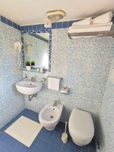 a blue tiled bathroom with a toilet and a sink at Hotel Bellini in Riccione