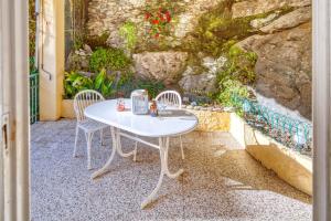 une table et des chaises blanches devant un mur en pierre dans l'établissement GIANLUCA Apartment, à Levanto