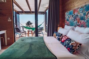 1 dormitorio con 1 cama y balcón con hamaca en Calheta Glamping Pods - Nature Retreat, en Calheta