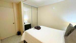 Un dormitorio con una cama blanca con una bolsa. en Cute Apartment with Patio and Laundry Pet Friendly en Ponce