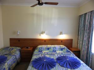 a bedroom with two beds with blue pillows on them at Panorama Seaside Apartments Norfolk Island in Burnt Pine