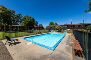 a swimming pool in a yard with a chair and a bench at Aston Suites - Sale in Sale