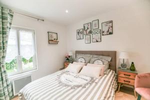 1 dormitorio con cama con sábanas a rayas y ventana en INSTANT FLEURY: maison de caractère, jardin secret en Barbizon