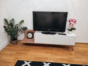 einen TV auf einem weißen Schrank mit Blumen und einer Uhr in der Unterkunft Apartman HANA in Travnik