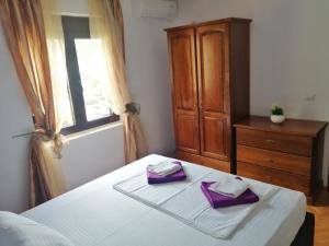 um quarto com uma cama e uma cómoda com guardanapos roxos em Apartment Golub em Budva