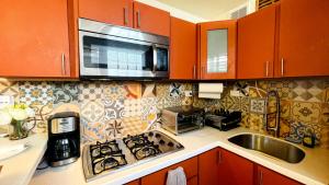 a kitchen with orange cabinets and a stove top oven at Cozy Studio Retreat with Private Parking and FREE Laundry in Ponce