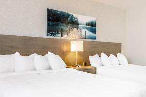 duas camas num quarto de hotel com almofadas brancas em Repotel Henri IV Québec em Cidade de Quebec