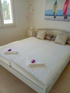 uma grande cama branca com duas flores roxas em Leo em Bilice