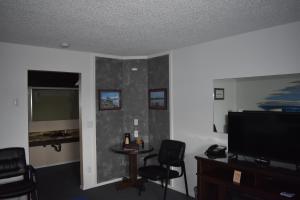 a living room with a table and chairs and a flat screen tv at Lighthouse Cove Inn in Bandon