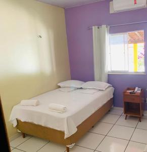 a bedroom with a bed with purple walls and a window at Pousada Luz - Santo Amaro do Maranhão in Santo Amaro