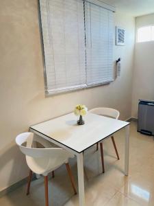 una mesa blanca con 2 sillas y un jarrón con flores en Charming Retreat with Patio Access and FREE Laundry en Ponce