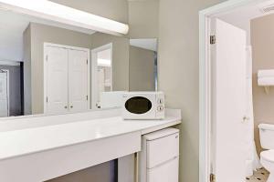 a bathroom with a microwave on a counter in front of a mirror at Days Inn by Wyndham Tucson City Center in Tucson