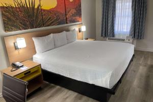 Un dormitorio con una cama grande y una mesa con teléfono. en Days Inn by Wyndham Tucson City Center en Tucson