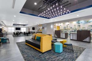 a lobby with a yellow couch and chairs and tables at La Quinta by Wyndham Tampa Central in Tampa