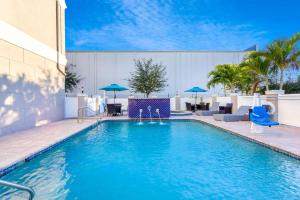 La Quinta by Wyndham Tampa Central في تامبا: مسبح والكراسي الزرقاء والمظلات