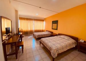 マチャラにあるHostal Solar Del Puertoのベッド2台とデスクが備わるホテルルームです。