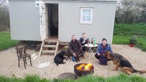 un groupe de personnes assises devant un hangar dans l'établissement Romantic secluded Shepherd Hut Hares Rest, à Southwick