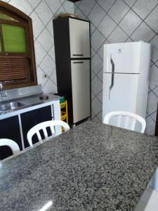 a kitchen with a refrigerator and a table with chairs at Casa na praia in Itapoa