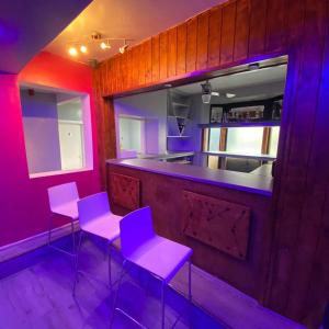 un bar con taburetes púrpura y una barra en una habitación en Glorious catering & Restaurant BnB en Ocker Hill