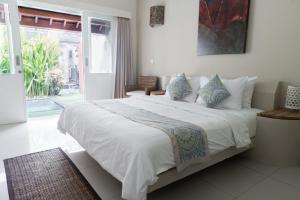 a bedroom with a large bed with white sheets and blue pillows at Scallywags Resort in Gili Trawangan +29 photos