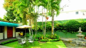a patio with a table and chairs and palm trees at Las Magnolias Hotel Boutique in San Salvador