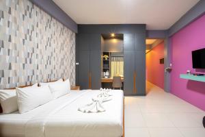 a bedroom with a large white bed and a tv at The Iconic Hotel Ranong in Ranong