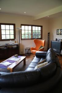 a living room with a leather couch and a table at Yallambee B&B in Bundanoon