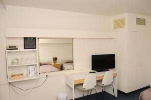 Peninsula Motor Inn في Tyabb: غرفة مع مكتب مع تلفزيون ومرآة