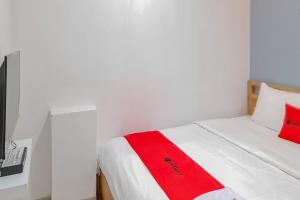 een slaapkamer met een rode deken op een bed bij RedDoorz Plus @ Batutulis Bogor in Bogor