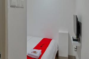 RedDoorz Plus @ Batutulis Bogor في بوغور: غرفة بيضاء مع سرير وبطانية حمراء
