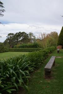 a park with a bench in the grass and plants at Yallambee B&B in Bundanoon