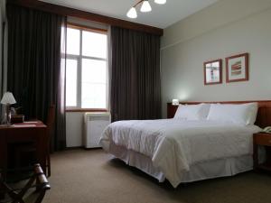 Habitación de hotel con cama grande y ventana en Gran Hotel Isabel Riquelme en Chillán