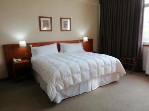 1 dormitorio con 1 cama blanca grande y 2 lámparas en Gran Hotel Isabel Riquelme, en Chillán