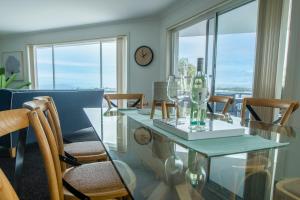 a dining room with a glass table and chairs at Top Of The Quays in Merimbula