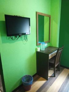 Habitación verde con escritorio y TV en la pared en Sky View Hotel Dengkil PUTRAJAYA, en Kampung Dengkil