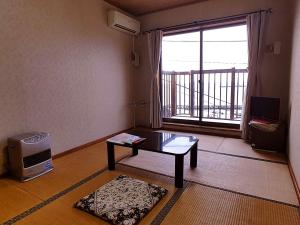 a living room with a table and a large window at Nanauraso in Sado