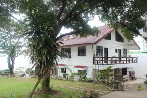 a white house with a palm tree in front of it at RedDoorz Hostel Hardin De Corales La Union in San Fernando