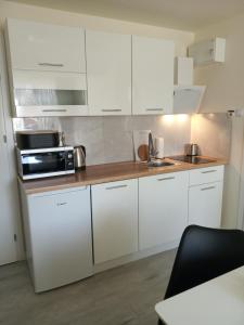 cocina con armarios blancos y microondas en Apartamenty Na Skale en Szklarska Poręba