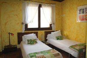 two beds in a room with a window at Molí del Casó B&B in Bagá