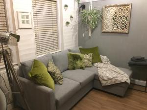 a gray couch with green pillows in a living room at OurStudio in Beverley