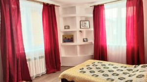 ミアスにあるГостевой дом в 5 мин от озера Тургояк первая линия до 14 человекの赤いカーテンとベッド、窓が備わるベッドルーム1室が備わります。