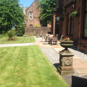 a yard with a stone planter in front of a house at Edenbank Hotel in Dumfries
