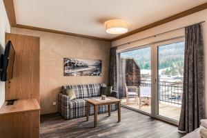 a living room with a couch and a balcony at Hotel Föhrenhof in Stanzach