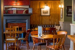 a restaurant with wooden tables and chairs and a fireplace at Howard Arms in Brampton