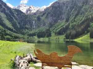 a wooden bird sculpture in front of a lake at Appartement BERGTRÄUME in Haus im Ennstal