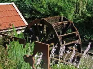 an old rusty water wheel sitting in the grass at Familie Heisch - Gemütliches Ferienhaus mit Terrasse und Strandkorb in Schafflund