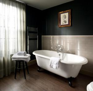 a bathroom with a white tub and a stool at The Crown And Thistle in Abingdon